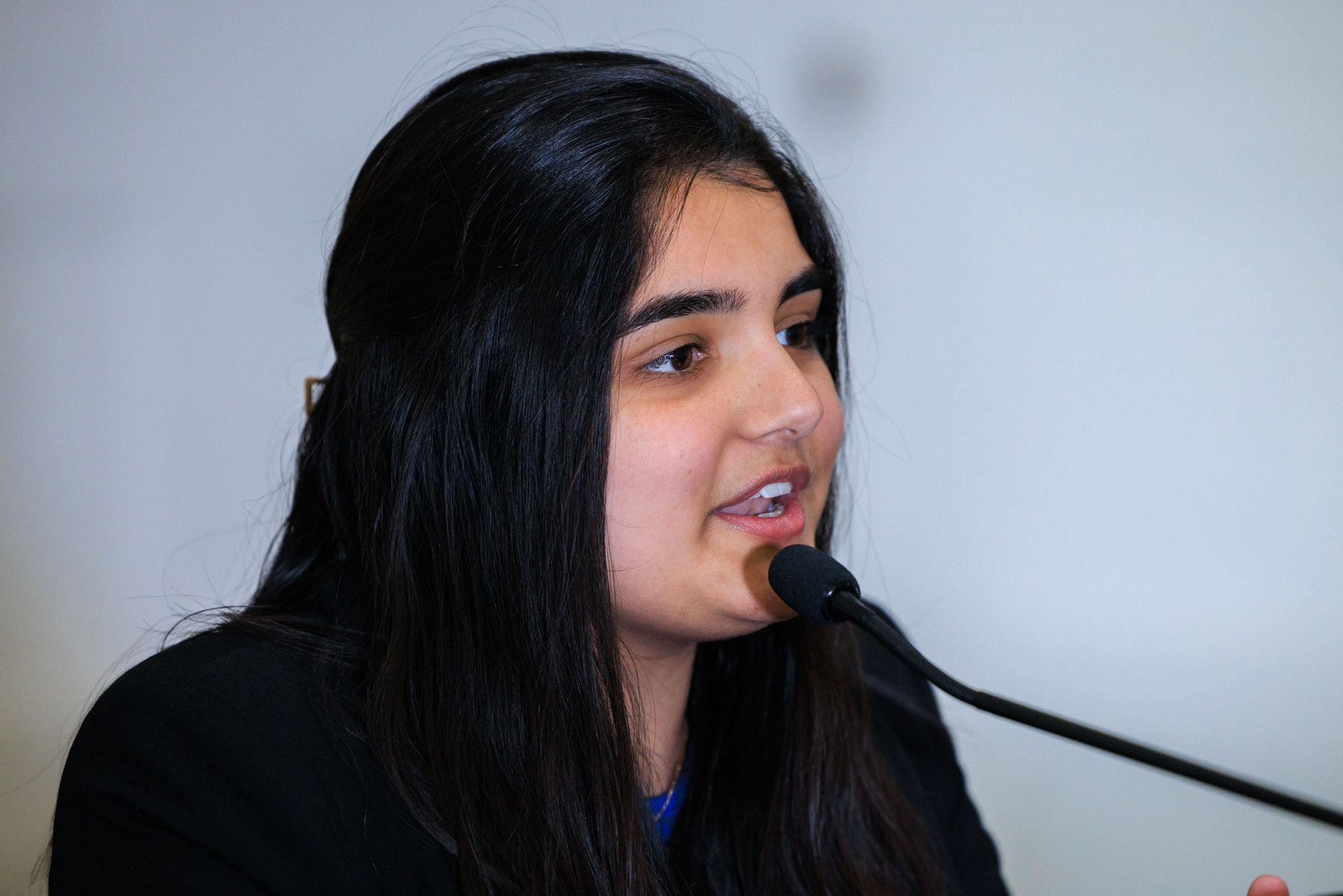 Pari Gulati speaking into a microphone during a community event